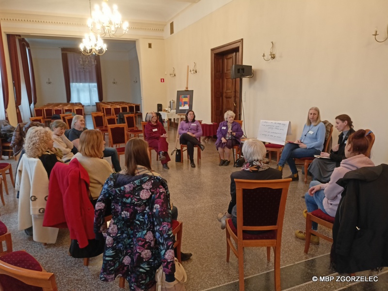 Kilkunastoosobowa grupa siedzi na krzesłach ustawionych w okrąg w dużej, dobrze oświetlonej sali, rozmawiając. Zdjęcie jest jednocześnie odnośnikiem do artykułu.