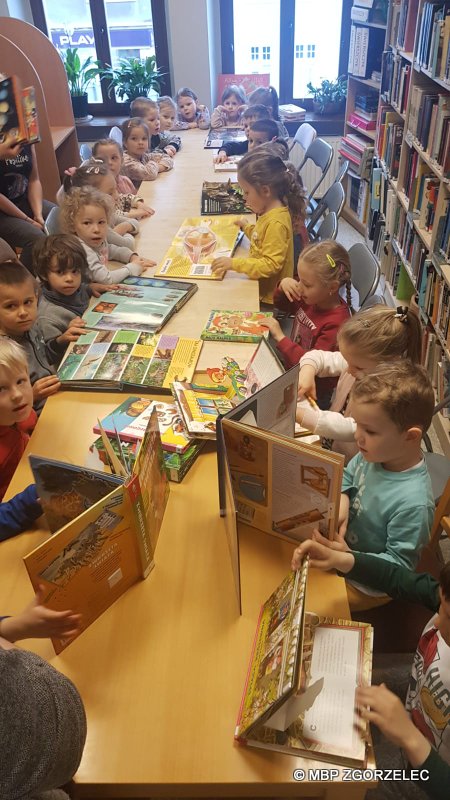 Grupa przedszkolaków oglądająca książki.