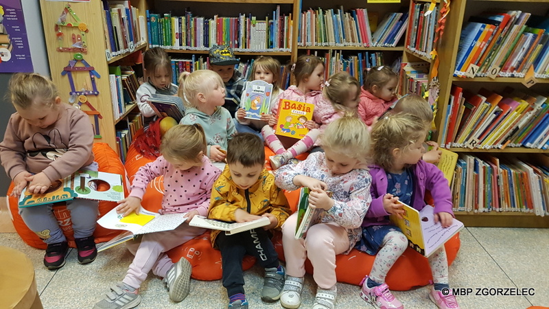 Grupa dzieci z Przedszkola nr 2 z zainteresowaniem przegląda książki  w Bibliotece