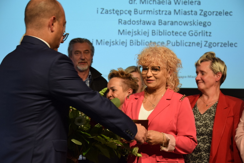 Burmistrz Miasta Zgorzelec Rafał Gronicz w otoczeniu bibliotekarzy, wręcza Dyrektor Miejskiej Biblioteki Publicznej w Zgorzelcu Krystynie Radziętej medal „Zasłużony dla Europa-Miasta Zgorzelec/Goerlitz”. 