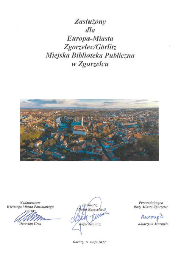 Dokument: Zasłużony dla Europa-Miasta Zgorzelec/Görlitz Miejska Biblioteka Publiczna w Zgorzelcu, podpisany przez: Nadburmistrza Miasta Goerlitz Octaviana Ursu, Burmistrza Miasta Zgorzelec Rafała Gronicza i Przewodniczącą Rady Miasta Zgorzelec Katarzynę Murmyło.