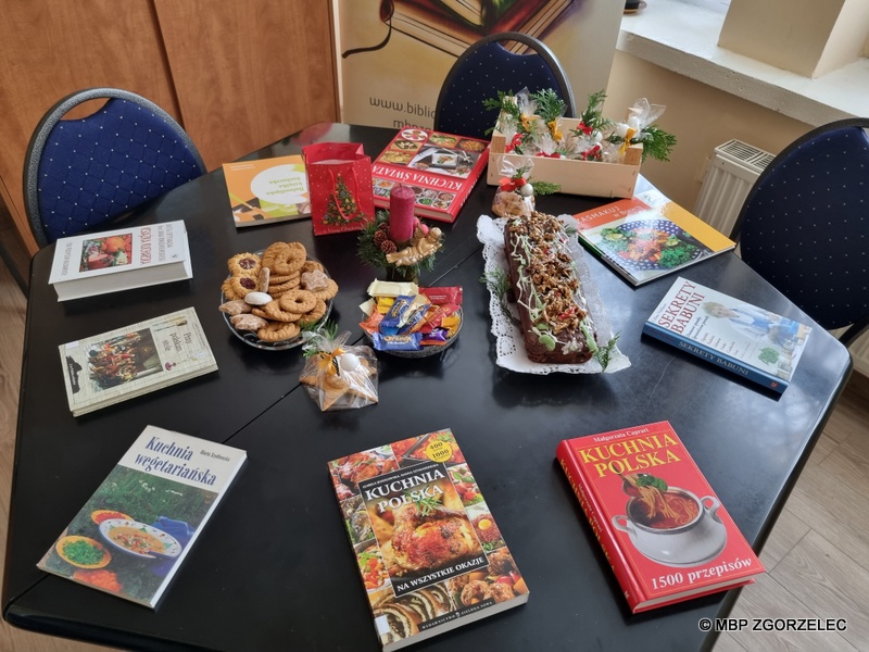 Dekoracja stołu: książki, świeczka, piernik, ciasteczka, cukierki.