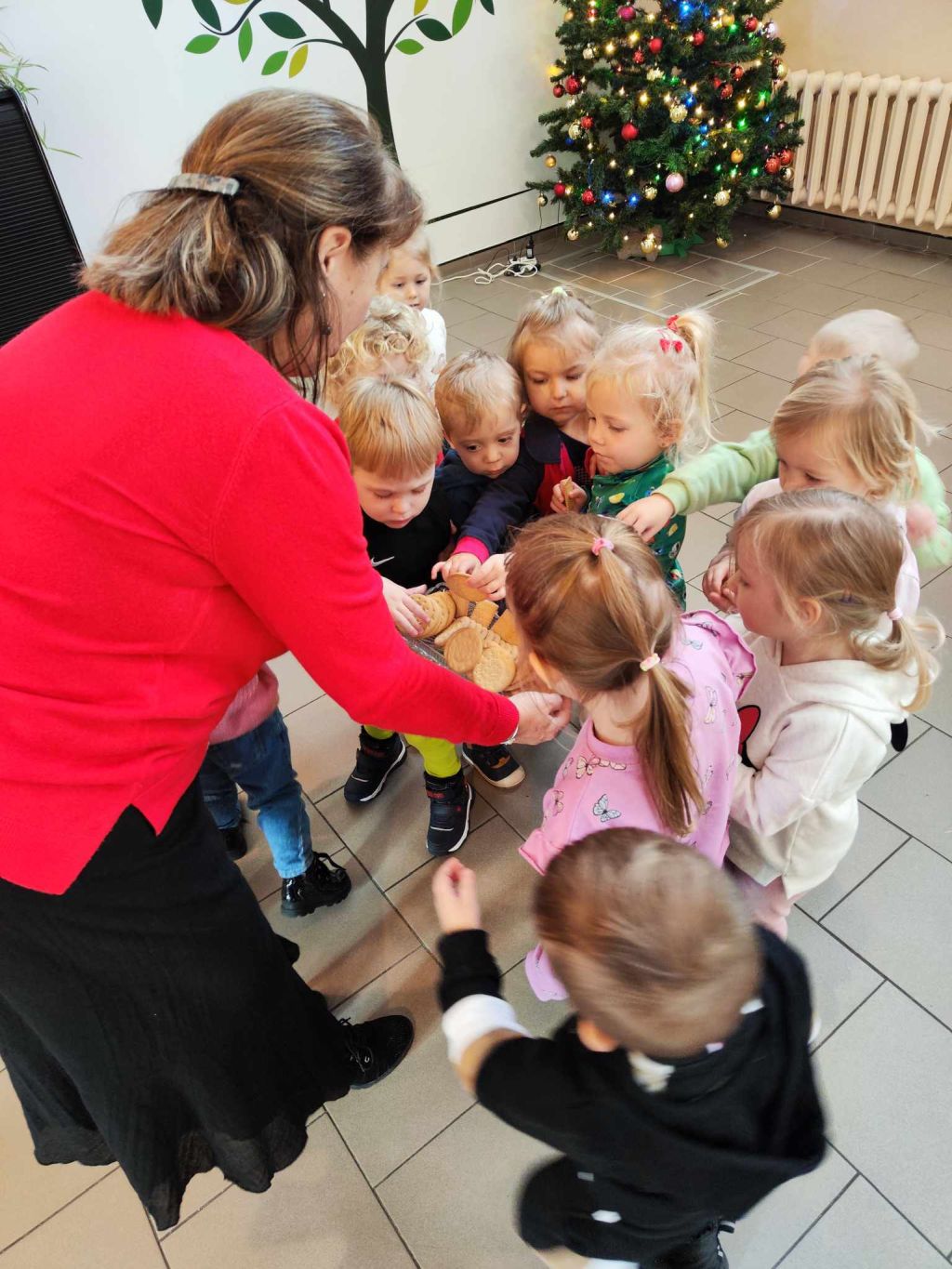 Bibliotekarka częstuje dzieci ciastkami.