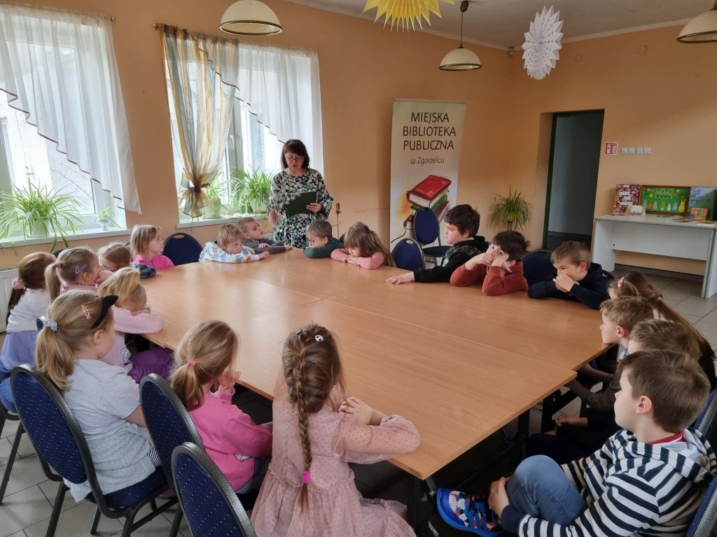 Dzieci słuchają opowiadania pt. "Bajeczka Wielkanocna", które czyta bibliotekarka. Zdjęcie jest odnośnikiem do wpisu "Bajeczka Wielkanocna".