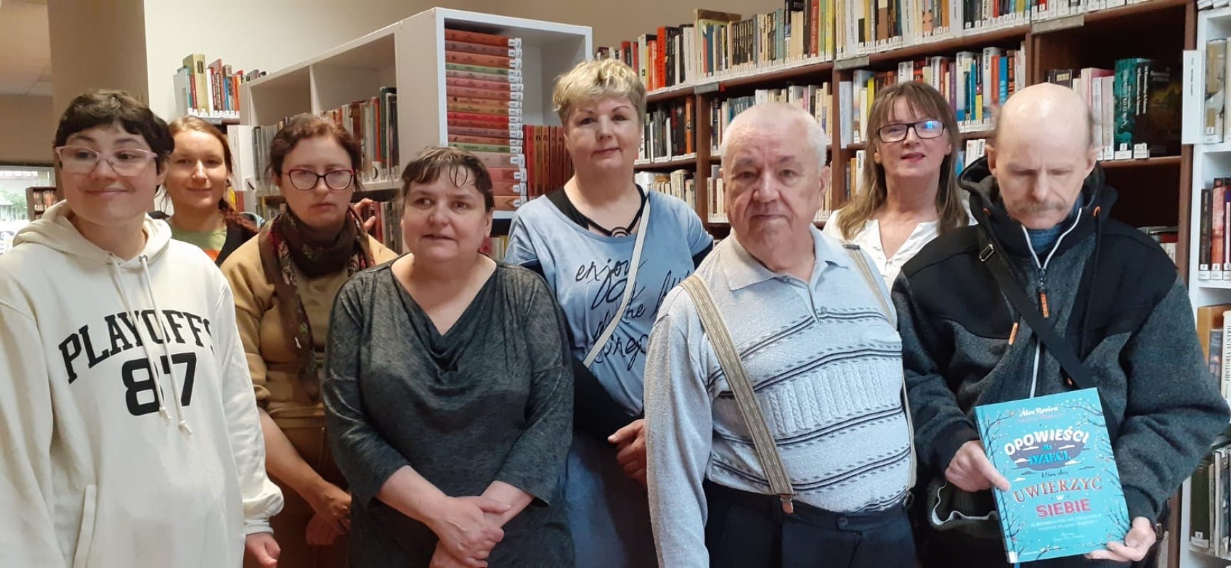 W pomieszczeniu bibliotecznym Filii nr 2, uczestnicy zajeć z Powiatowego Ośrodka Wsparcia w Zgorzelcu wraz z bibliotekarkami pozują do wspólnego zdjęcia.