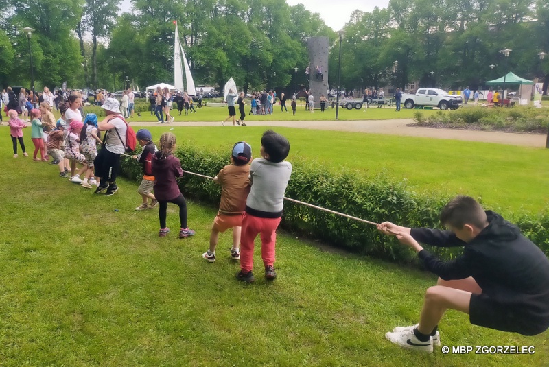 Na skwerze ks. Jerzego Popiełuszki grupa dzieci bierze udział w zabawie przeciągania liny.