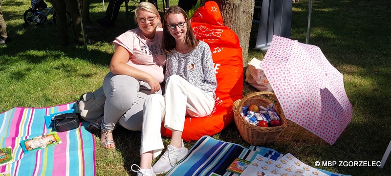 Na terenie otaczającym Fort Bolka i Lolka siedzą dwie kobiety i z uśmiechem pozują do wspólnego zdjęcia. Na terenie otaczającym Fort Bolka i Lolka siedzą dwie kobiety i z uśmiechem pozują do wspólnego zdjęcia.