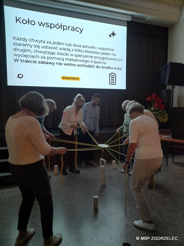 W sali widowiskowej Miejskiego Domu Kultury w Zgorzelcu siedem osób próbuje zbudować wieżę z drewnianych klocków.