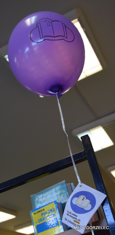 Fioletowy balon z nadrukowanym logiem akcji "Książki w chmurach" i z przyczepioną wstążeczką z kodem do e-podręcznika