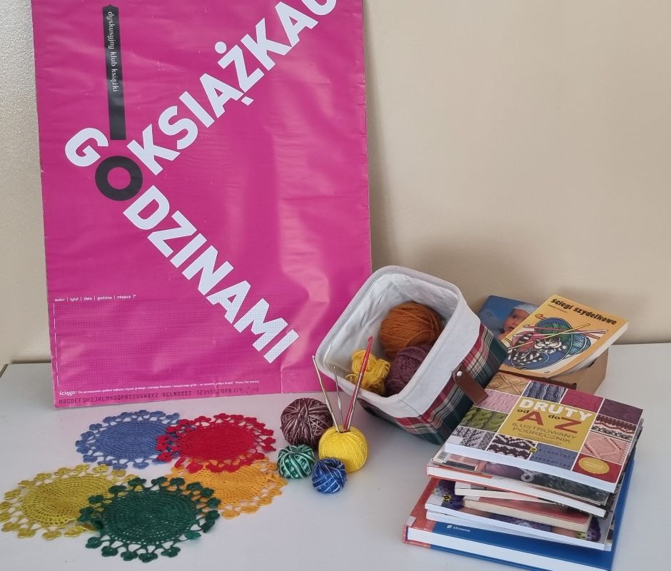 Wystawka złożona z książek o szydełkowaniu, włóczki, serwetek i baneru Dyskusyjnego Klubu Książki