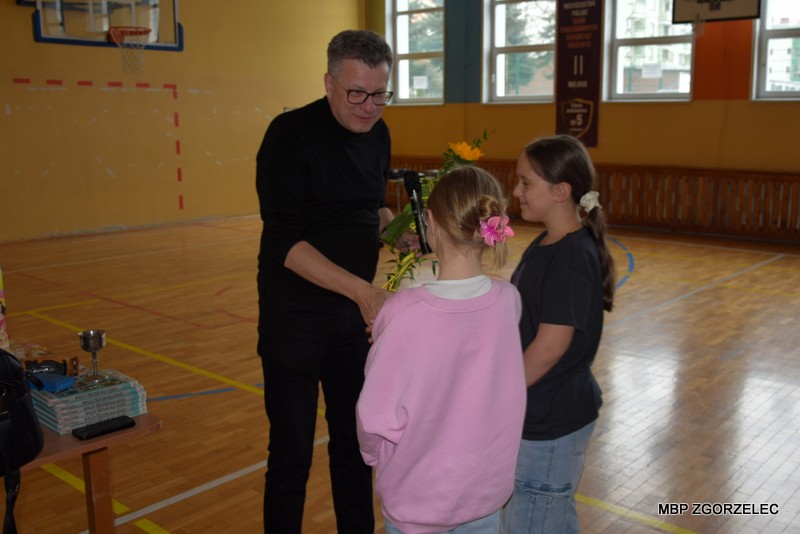 W pomieszczeniu sali gimnastycznej Szkoły Podstawowej nr 5 im. Marii Skłodowskiej-Curie, dzieci dziękują panu Markowi Michalakowi za spotkanie.