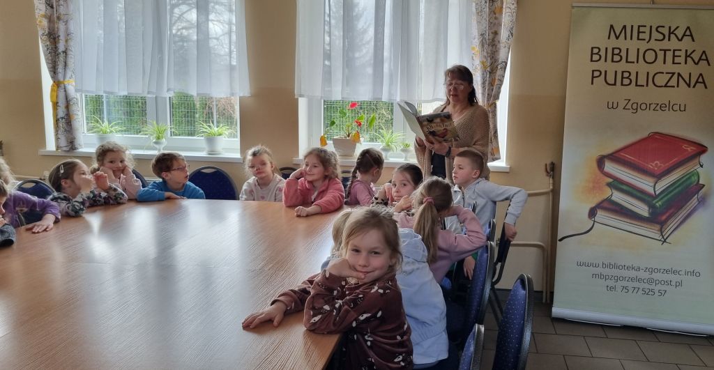 Bibliotekarka czyta dzieciom bajkę pt. "Kukuryku! Afera w kurniku".