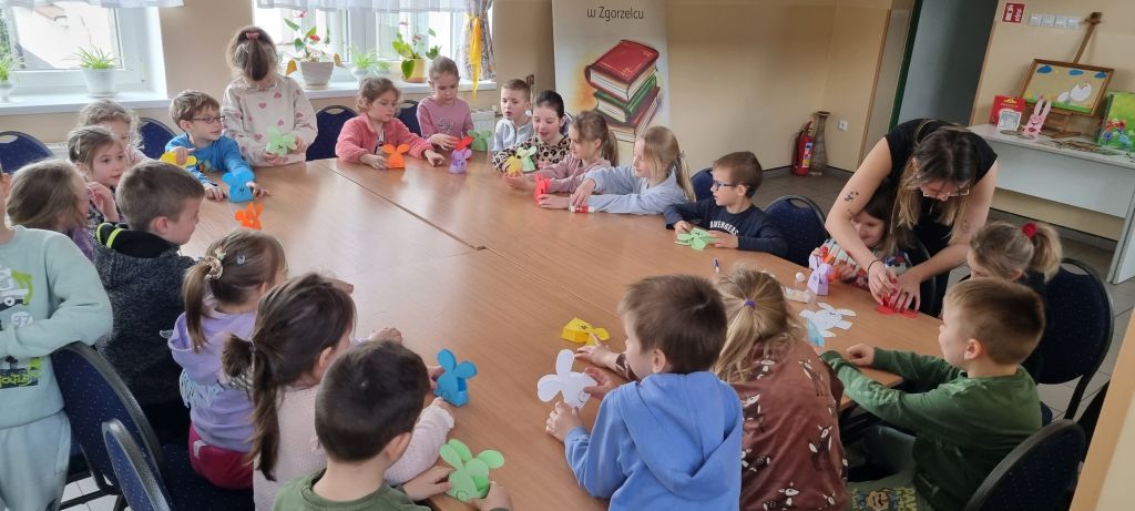 Dzieci podczas zajęć w bibliotece wyklejają zające.