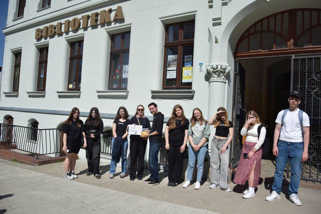 Uczestnicy akcji społeczno-edukacyjnej Żonkile pozują do zdjęcia przed kamienicą, w której mieści się siedziba Miejskiej Biblioteki Publicznej w Zgorzelcu. Zdjęcie jest odnośnikiem do wpisu "Żółte żonkile symbolem pamięci".