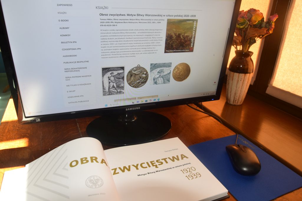 Stanowisko komputerowe w Czytelni MBP. Przed monitorem komputera leży rozłożona książka. Zdjęcie jest odnośnikiem do wpisu "15 sierpnia - Święto Wojska Polskiego".