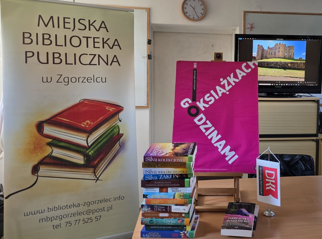 Ustawione na stole bannery, promujące czytelnictwo i Miejską Bibliotekę w Zgorzelcu. Obok leżą książki beletrystyczne różnych autorów.