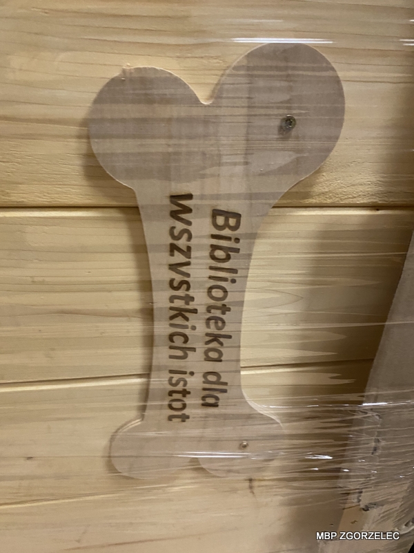 Drewniana kość z wygrawerowanym napisem "Biblioteka dla wszystkich istot"