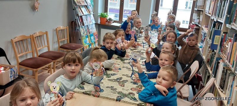 Prezentacja prac plastycznych – dzieci siedzą przy stole i pokazują pokolorowane papierowe misie.