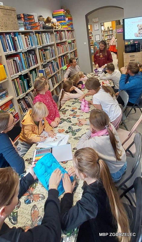 Warsztaty mydełkowe – dzieci siedzą przy stole z kolorowymi miskami i silikonowymi foremkami, przygotowują się do warsztatów robienia mydełek.