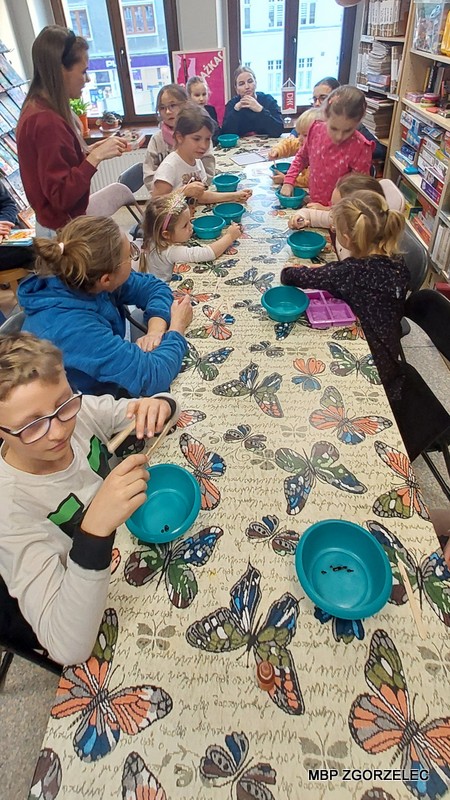 Warsztaty mydełkowe – dzieci siedzą przy stole z kolorowymi miskami i silikonowymi foremkami, przygotowują się do warsztatów robienia mydełek.