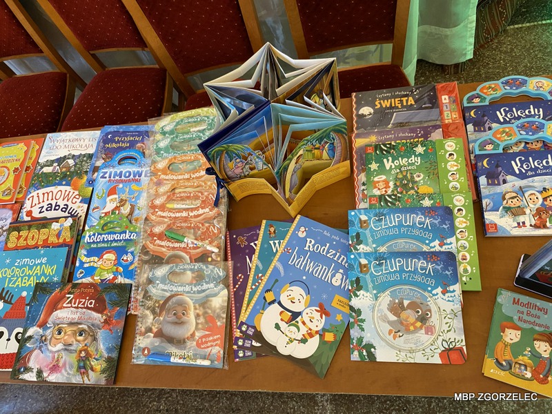 Na drewnianym stole rozłożone są książki dla dzieci o tematyce świątecznej. Na drewnianym stole rozłożone są książki dla dzieci o tematyce świątecznej.