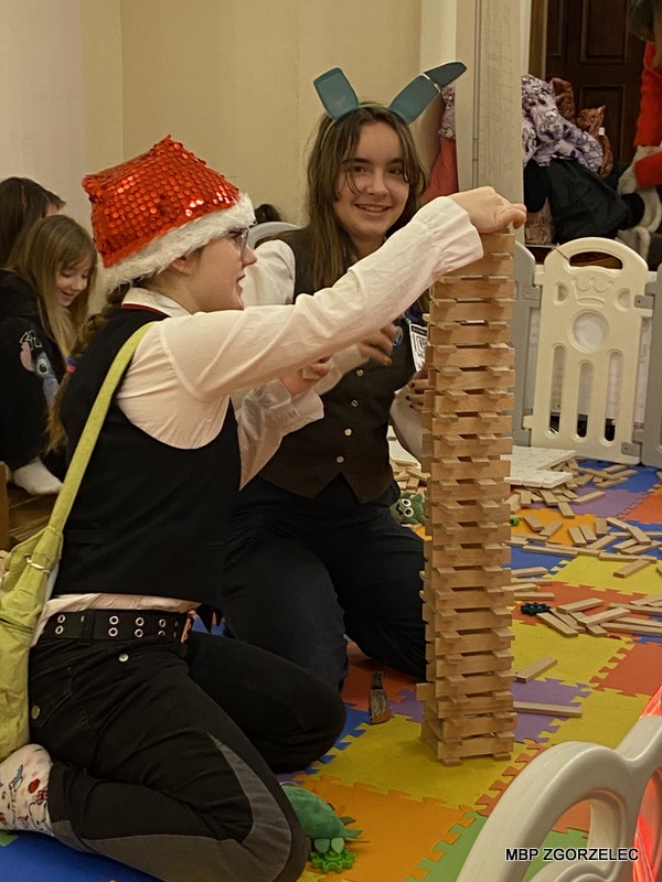 Dwie młode dziewczyny buduje wieżę z klocków na kolorowej macie Dwie młode dziewczyny buduje wieżę z klocków na kolorowej macie