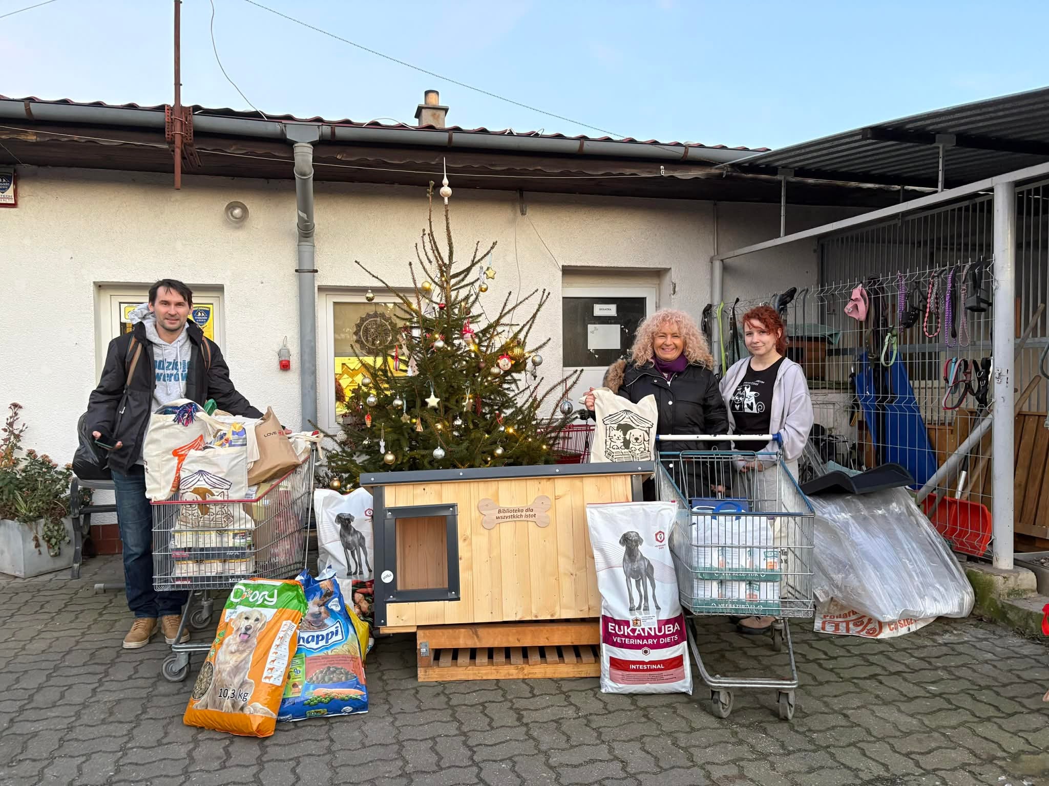 Przed Schroniskiem dla Zwierząt Małych w Dłużynie Dolnej stoją 3 osoby: przedstawiciele Miejskiej Biblioteki Publicznej w Zgorzelcu oraz Schroniska. 