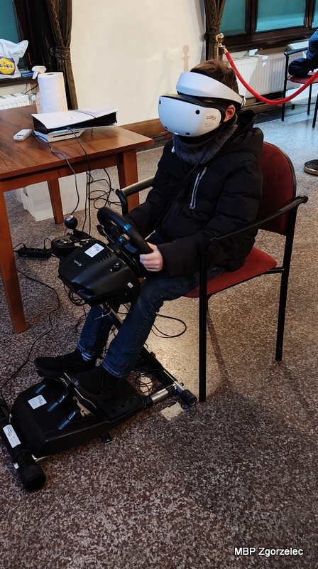 Dziecko korzysta z&nbsp;symulatora jazdy wyposażonego w&nbsp;kierownicę i&nbsp;gogle VR podczas finału WOŚP w&nbsp;MDK Zgorzelec.