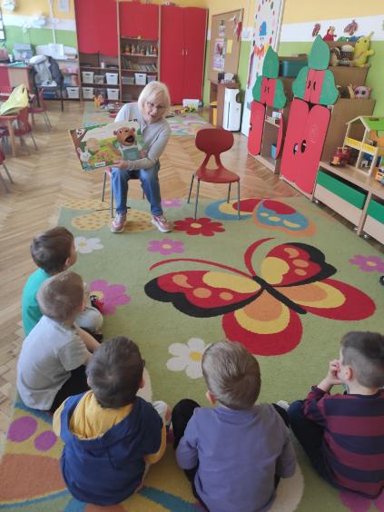 Bibliotekarka pokazuje przedszkolakom ilustrację z książki. Zdjęcie jest odnośnikiem do wpisu "Bajkowe spotkania".