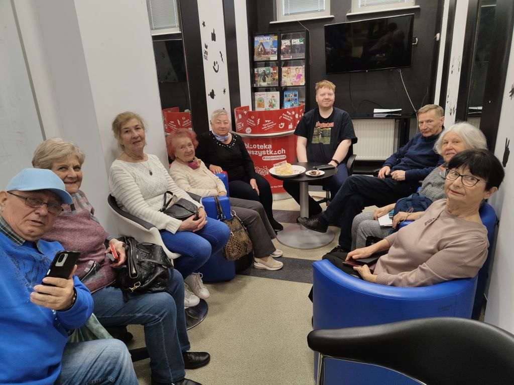 Uczestnicy zajęć edukacji cyfrowej dla seniorów pozują do wspólnego zdjęcia razem z bibliotekarzem prowadzącym zajęcia w Filii nr 1 przy ul. Orzeszkowej 30a. Zdjęcie jest odnośnikiem do wpisu 
