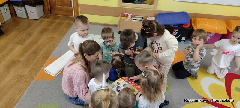 Dzieci z&nbsp;Kasztankowego Przedszkola siedzą na dywanie i&nbsp;wspólnie oglądają książkę obrazkową o&nbsp;tematyce wiejskiej, uczestnicząc w&nbsp;zajęciach czytelniczych.