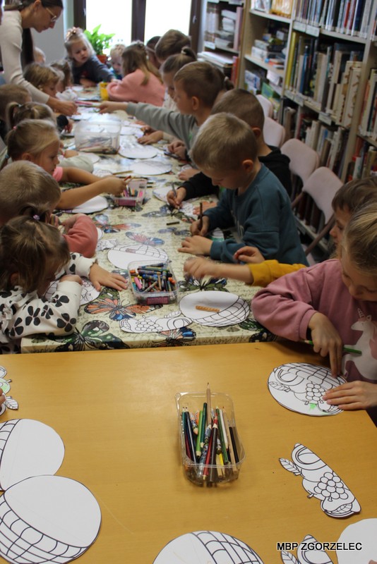 Uczestnicy zajęć bibliotecznych kolorują przygotowane ilustracje warzyw, korzystając z&nbsp;kredek i&nbsp;materiałów plastycznych.